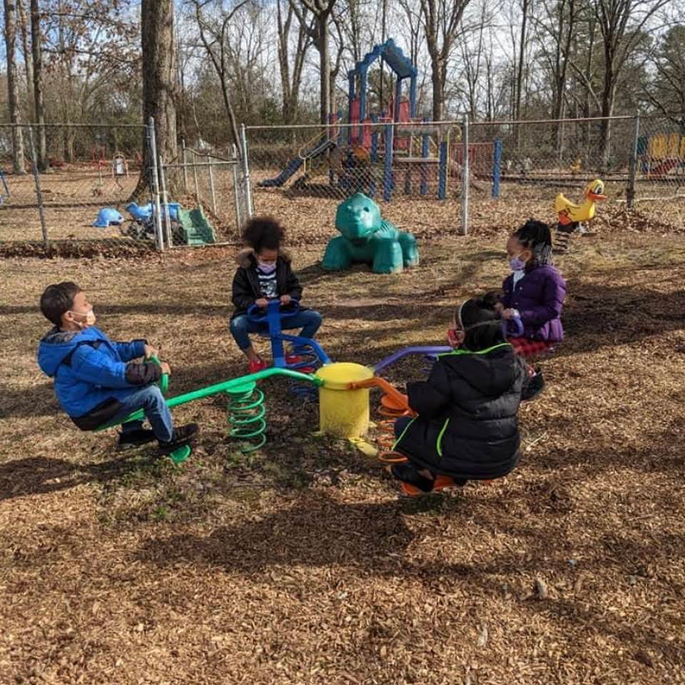 Children playing on a seesaw and other playground equipment