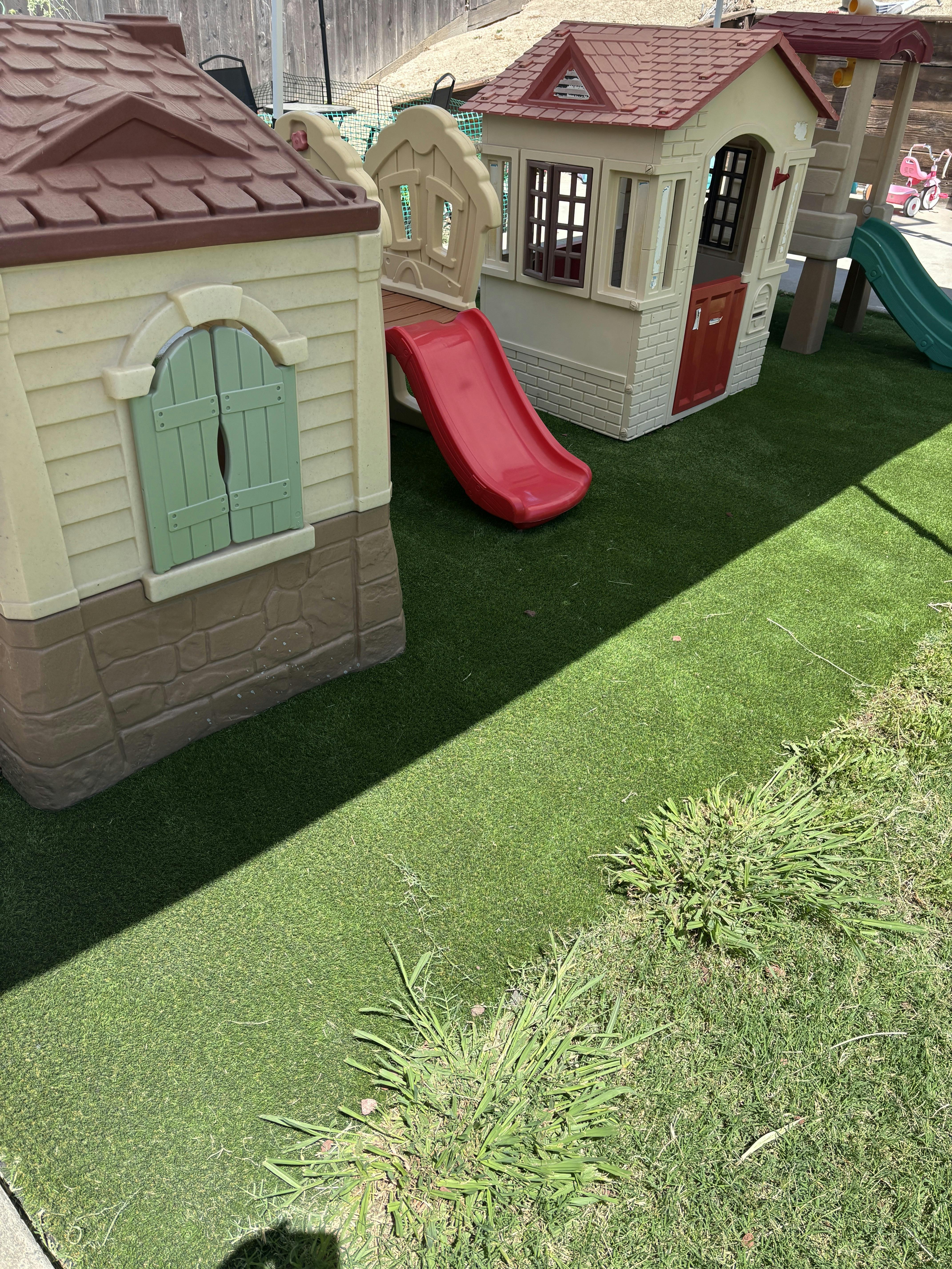Plastic playhouses with slides on artificial turf in a yard