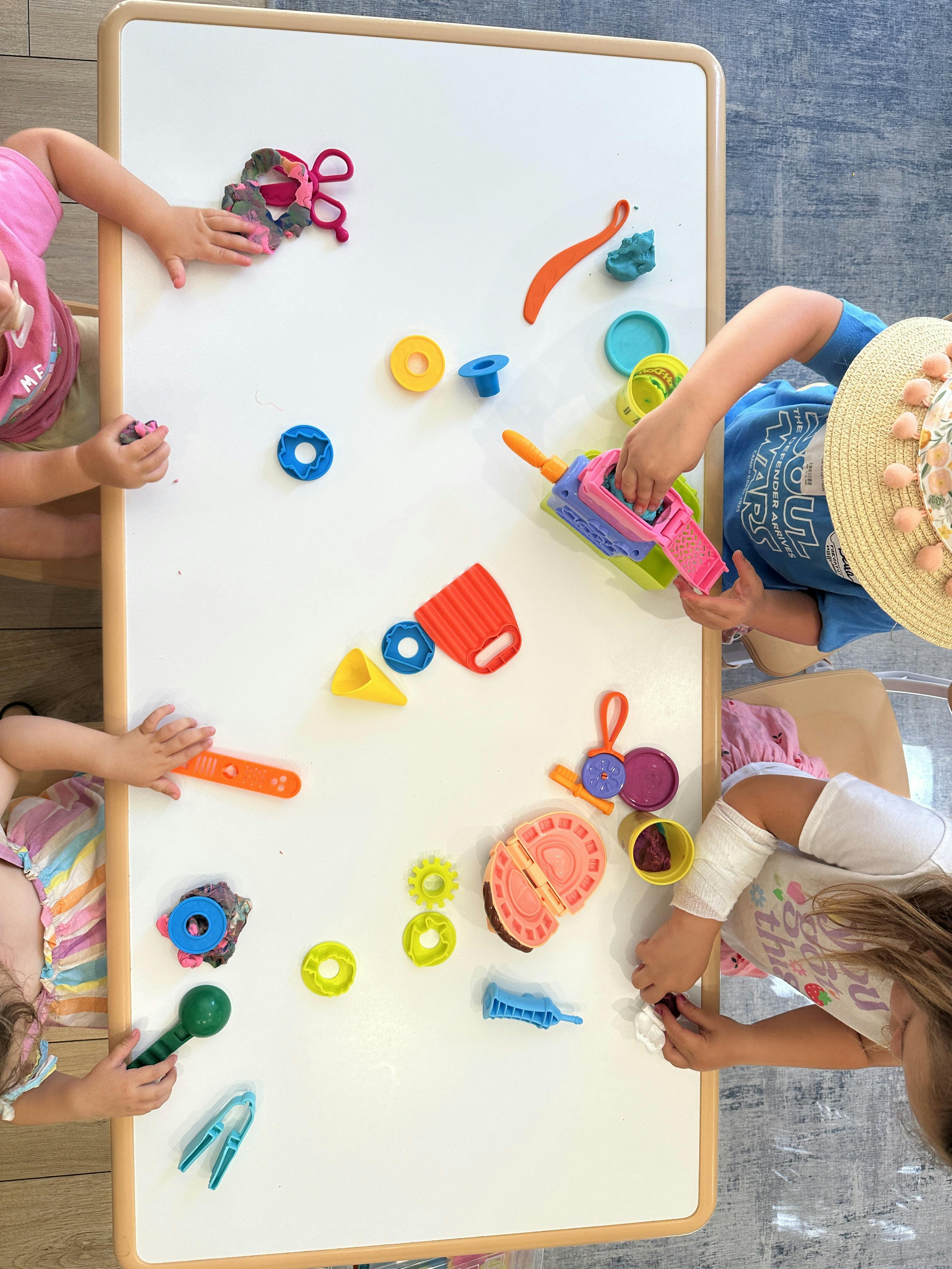 Children playing with colorful toys on a white table