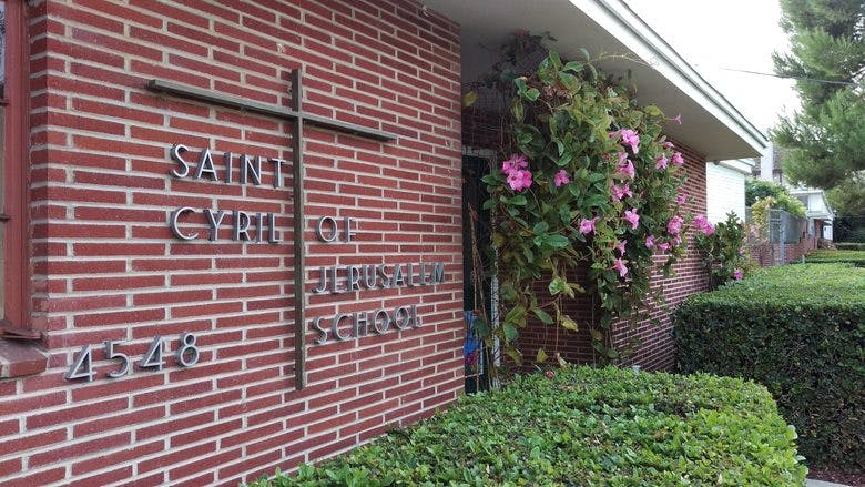 Red brick building with a cross and "Saint Cyril of Jerusalem School" sign