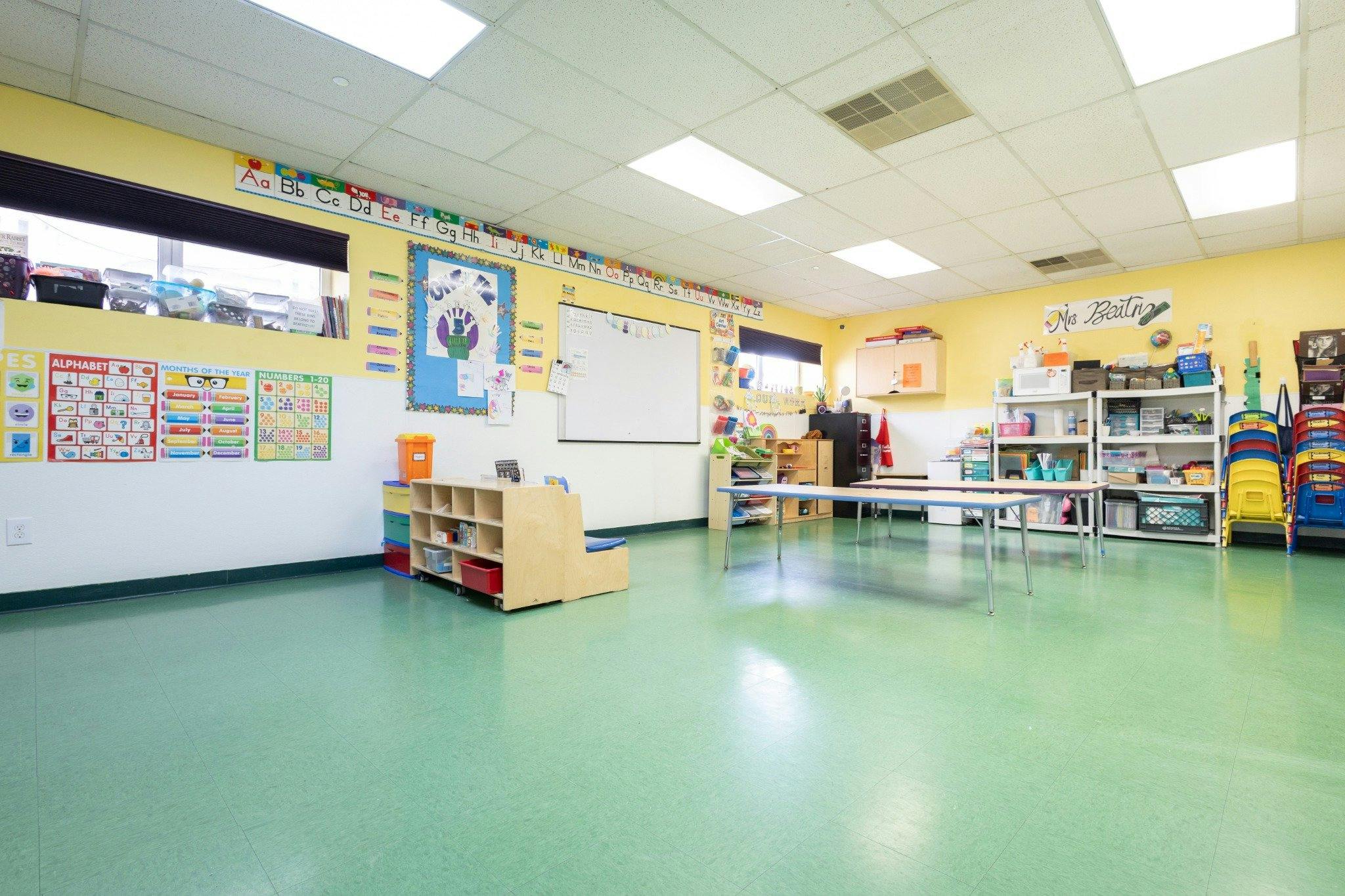Classroom interior with educational posters, tables, and storage shelves
