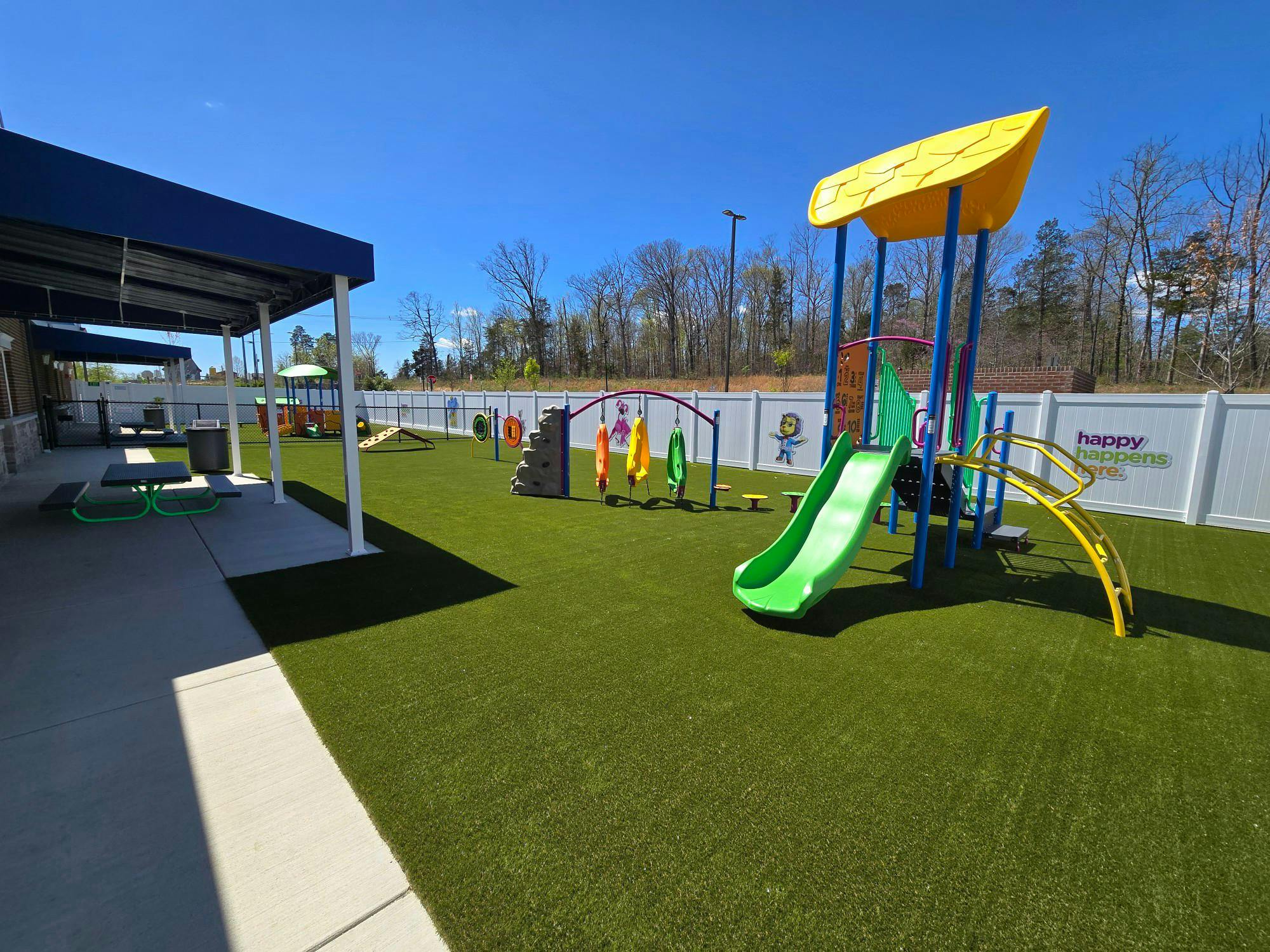 Outdoor playground with green turf, slide, and climbing structures