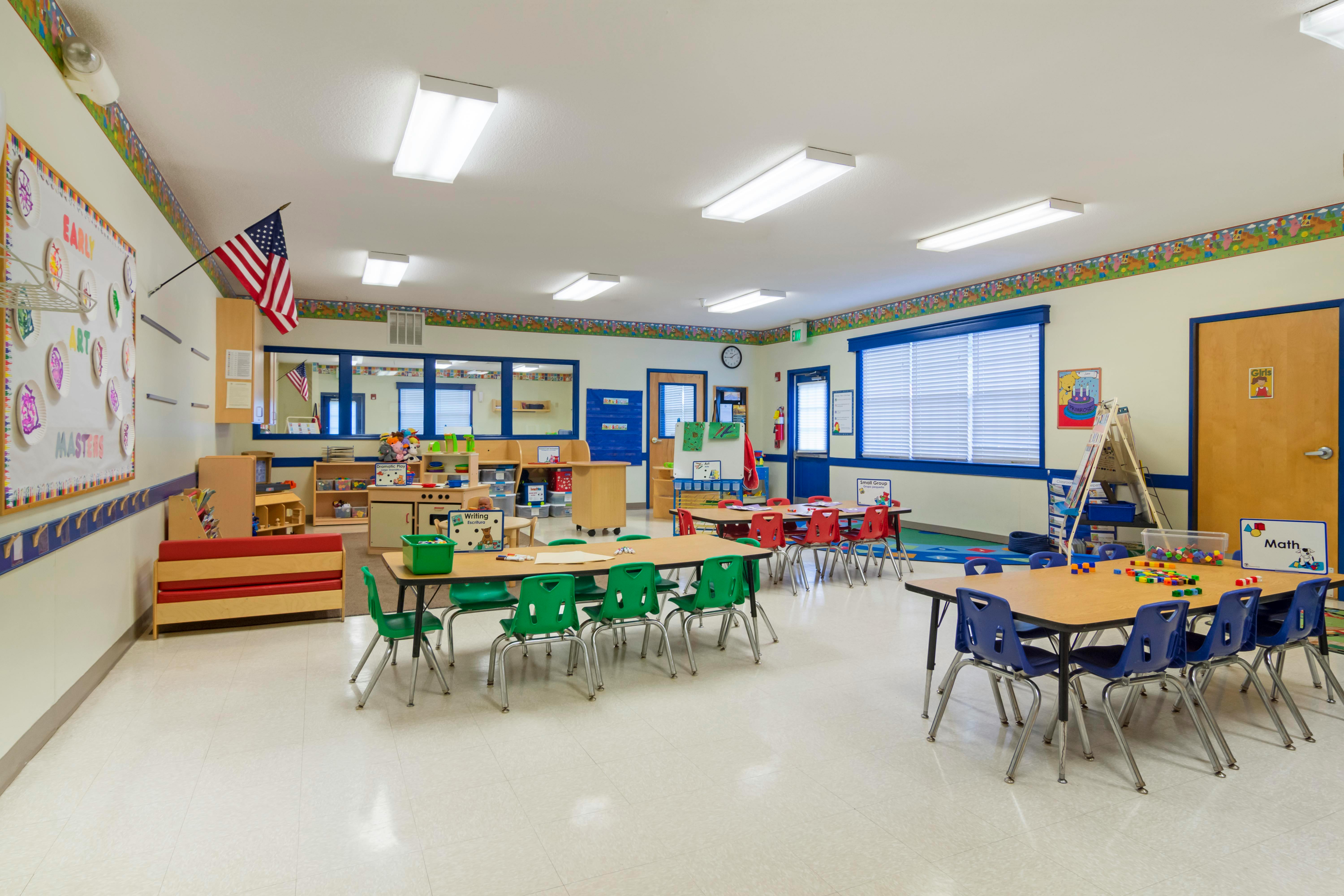 Classroom with small tables and chairs, toys, and learning materials