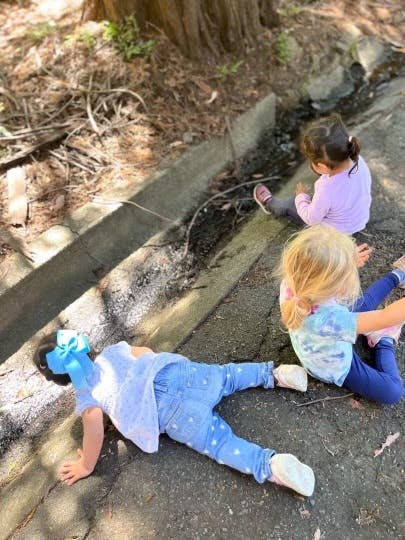 Three children playing on the ground outdoors