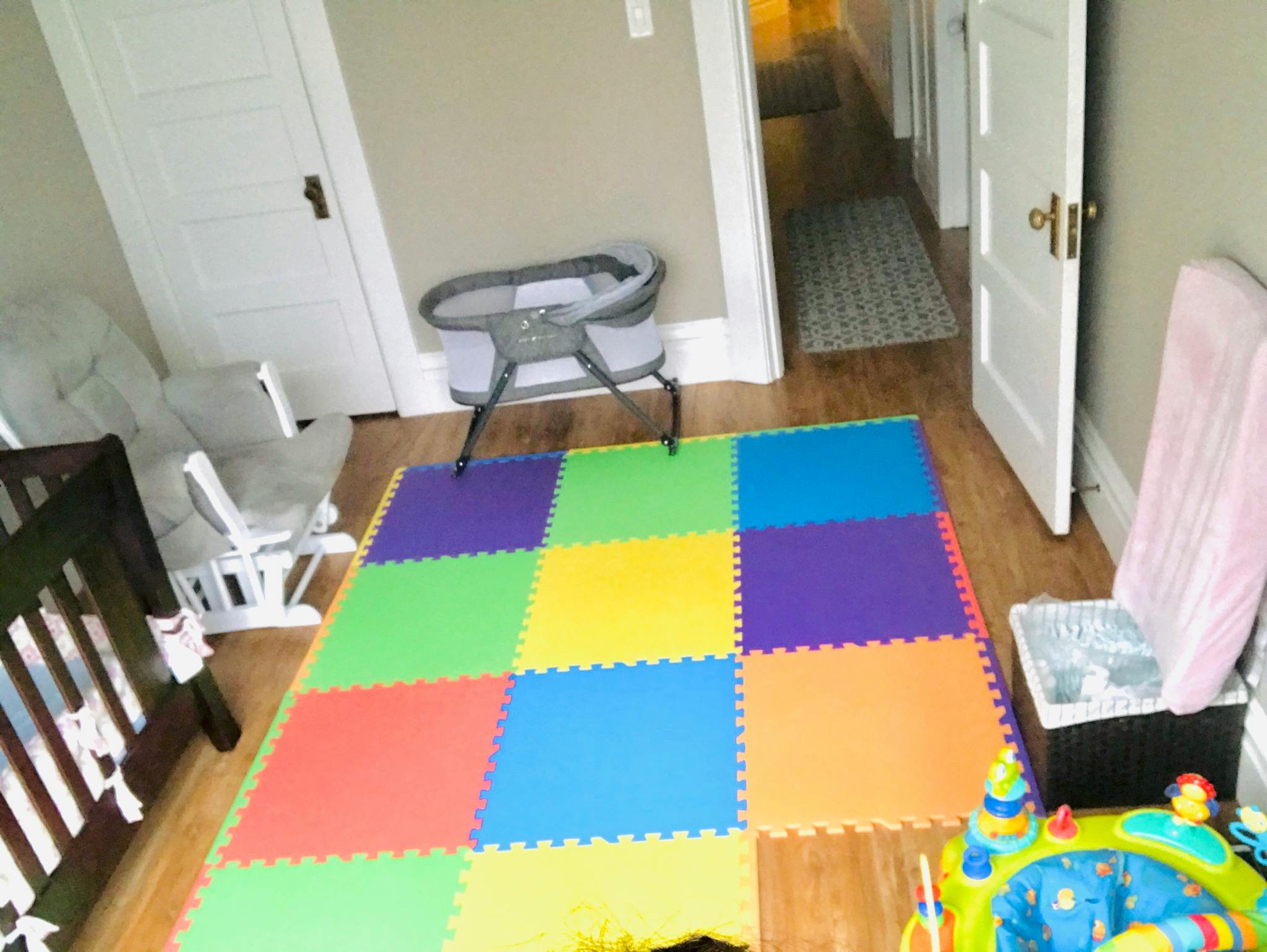 Nursery room with a crib, bassinet, and colorful play mat