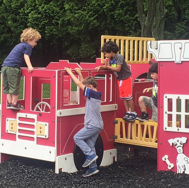Children playing on a red fire truck-shaped playground structure