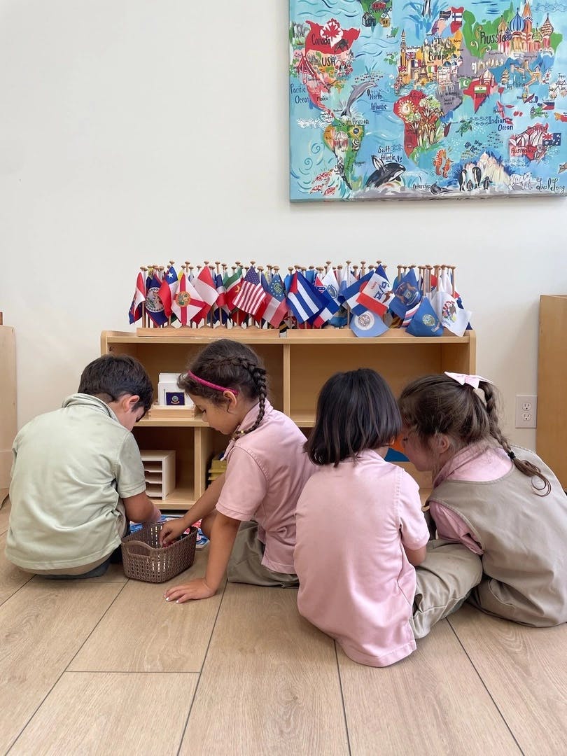 Children sitting on the floor playing with items from a shelf