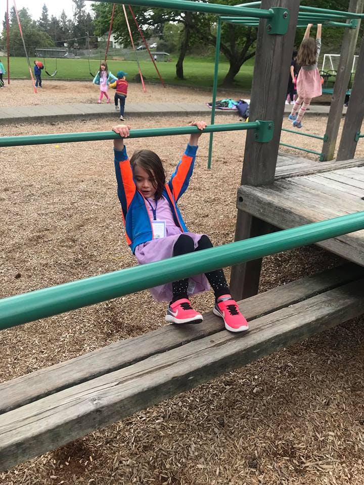 Child hanging from monkey bars on a playground