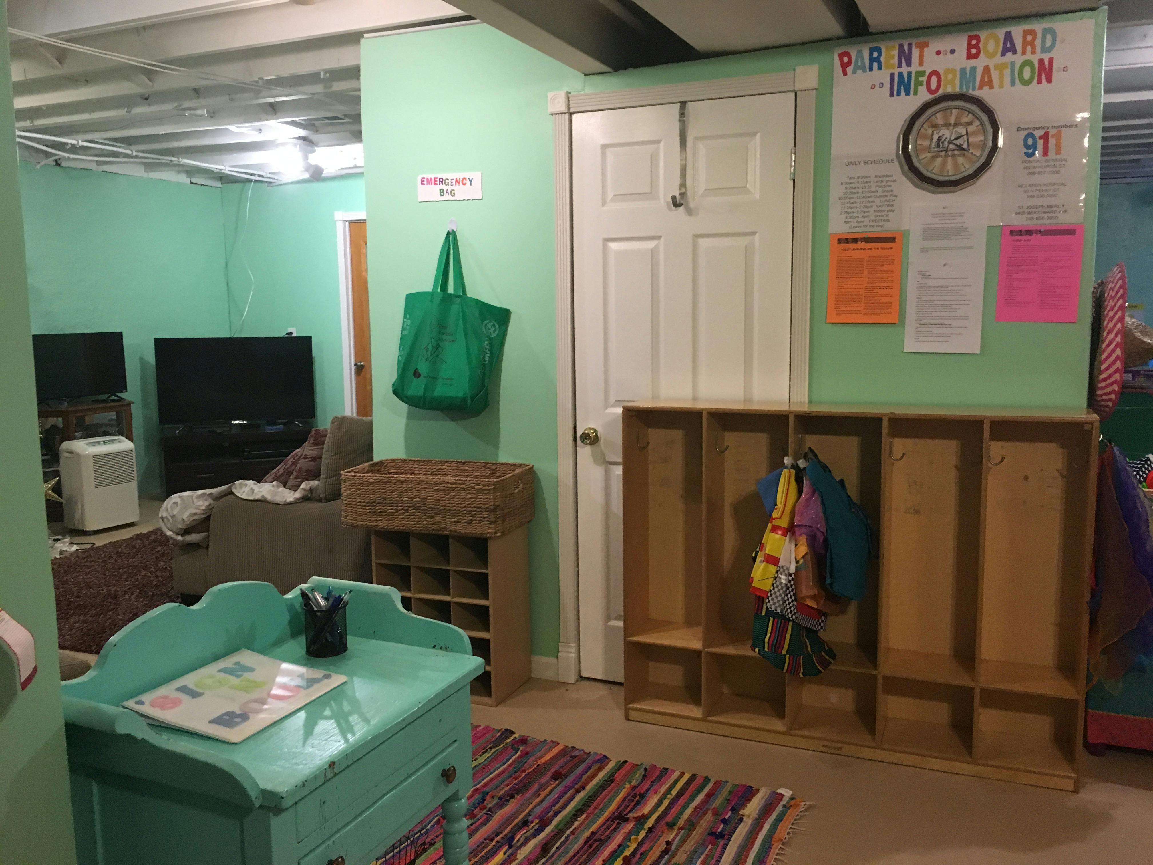Room with green walls, white door, wooden cubbies, and a TV area