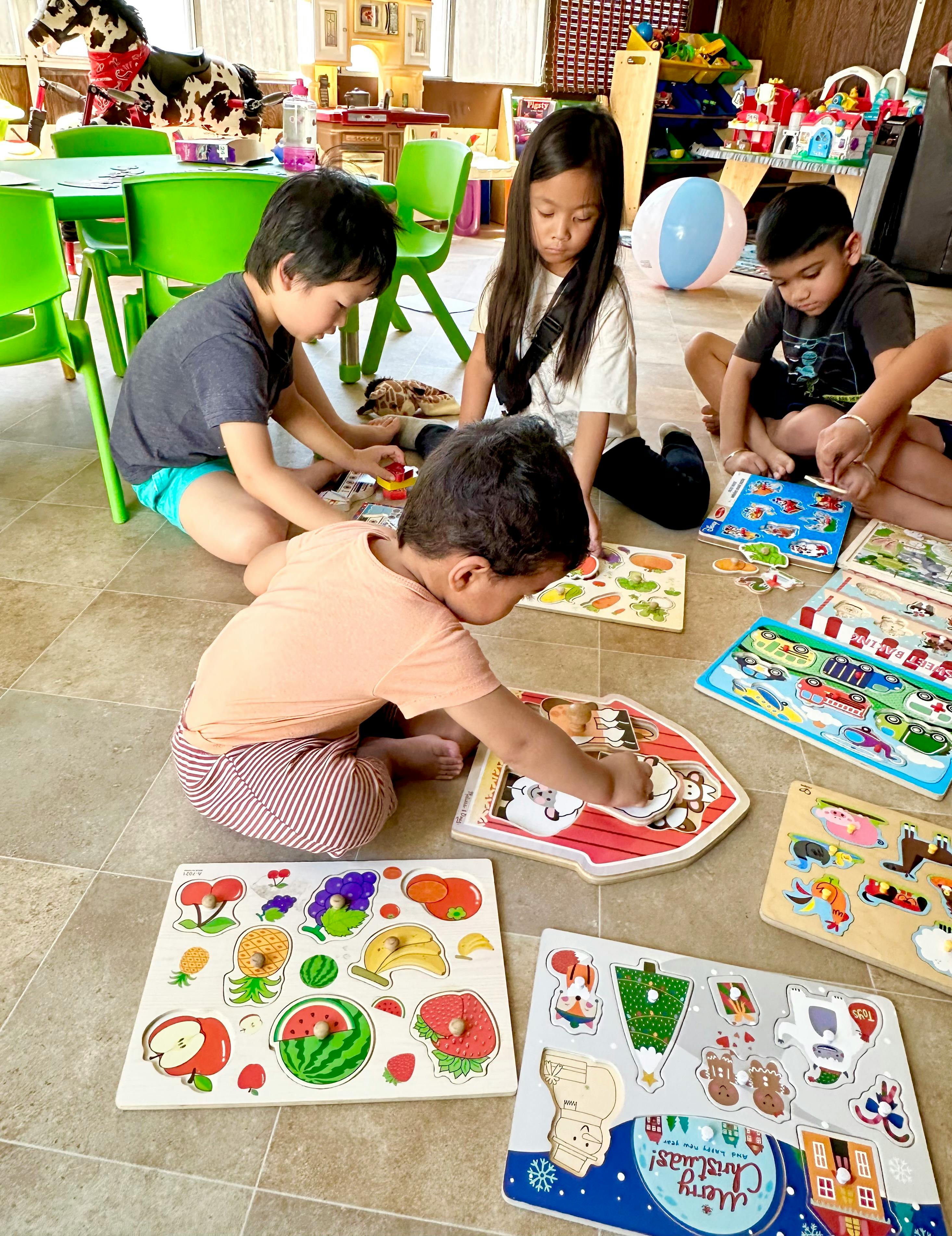Four children sitting on the floor playing with puzzles