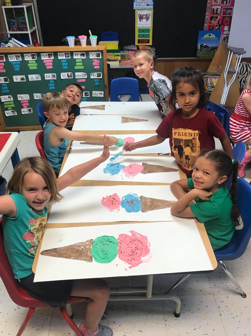 Children making ice cream cone art projects in a classroom