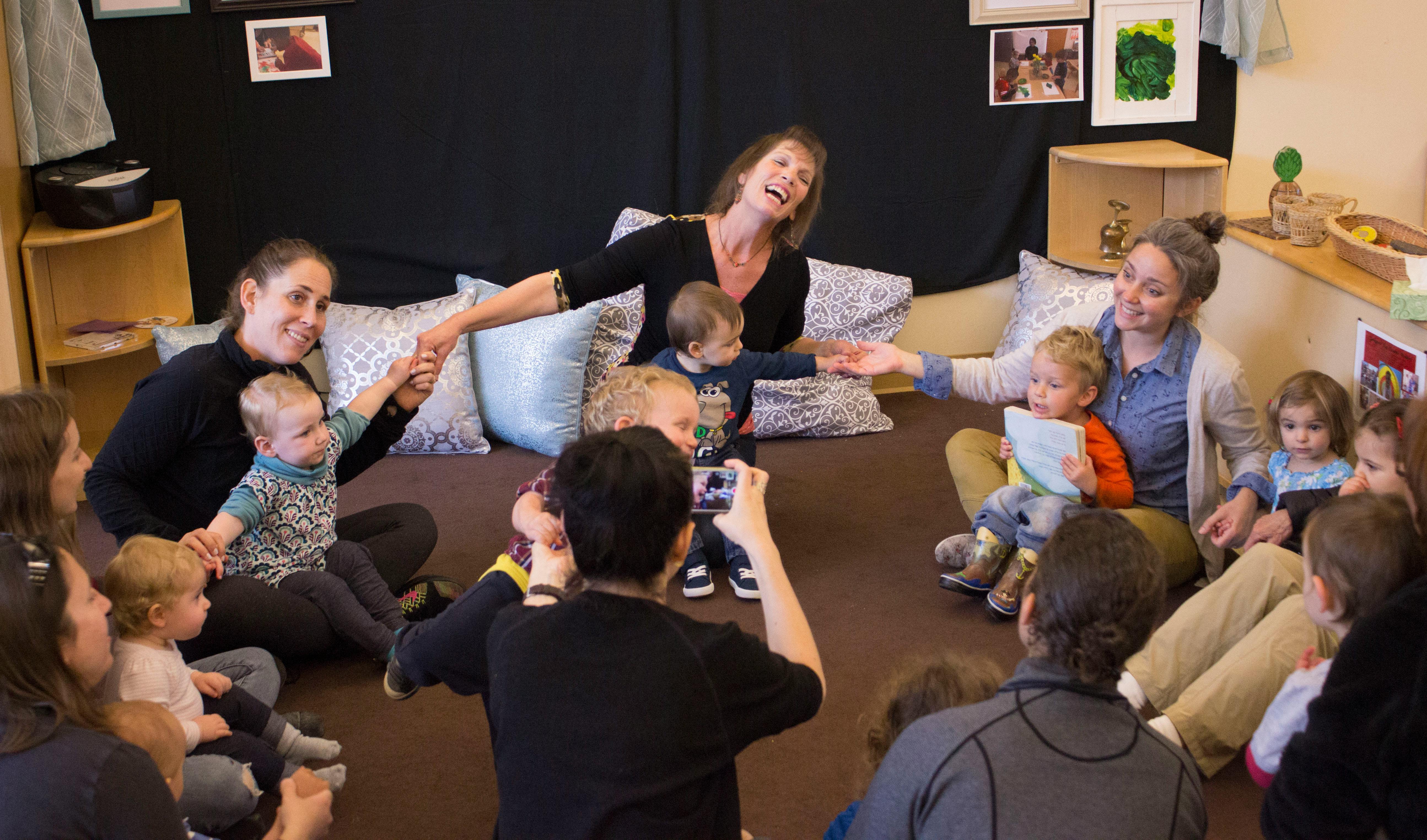 Adults and children sitting in a circle, some holding hands