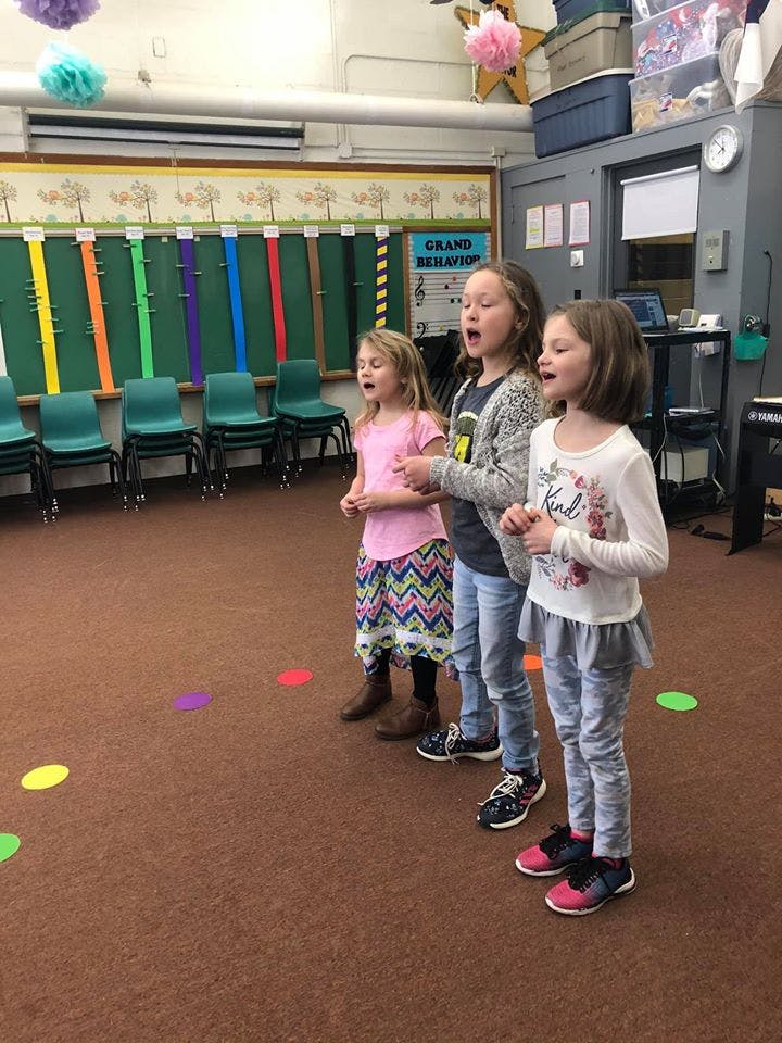 Three children singing in a classroom