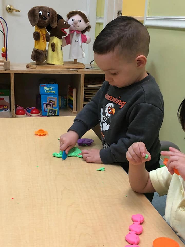Child playing with green playdough at a table