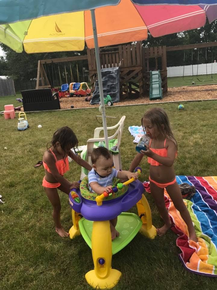 Two children and a baby in a play saucer outdoors