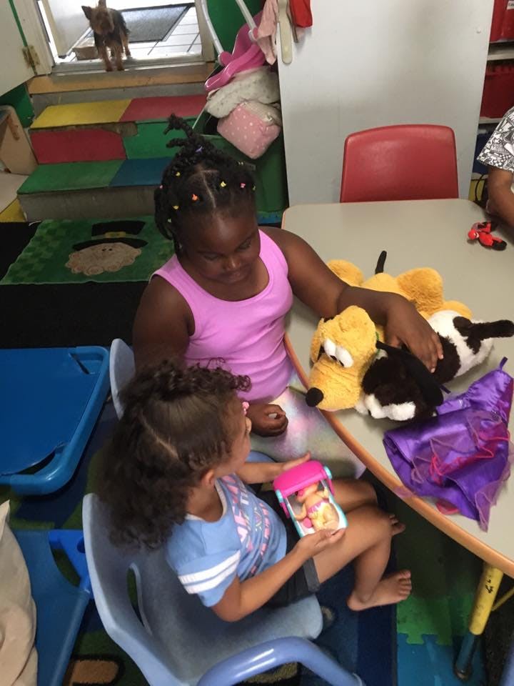 Two children playing with stuffed animals at a table
