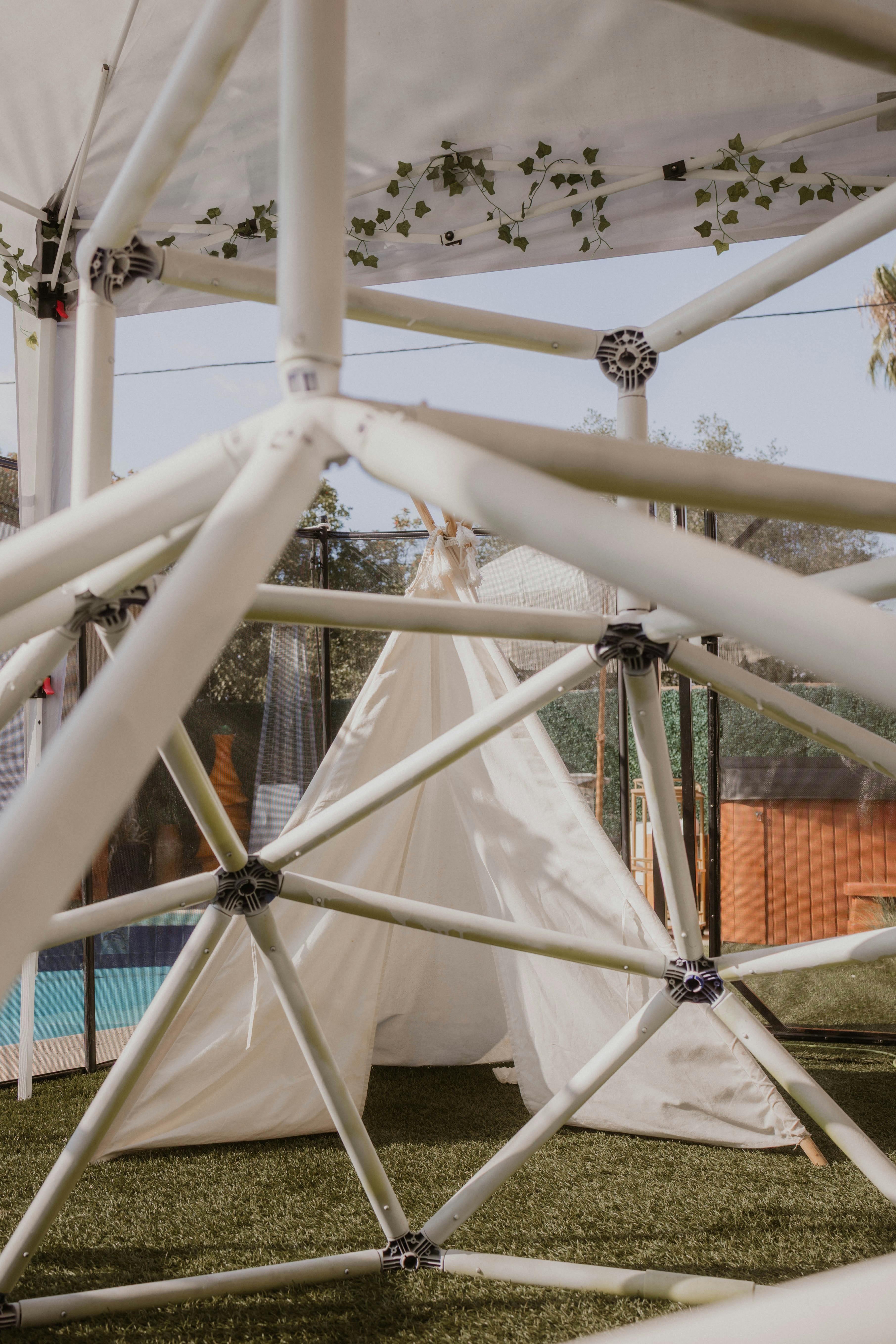 White geodesic dome frame over a white tent on grass