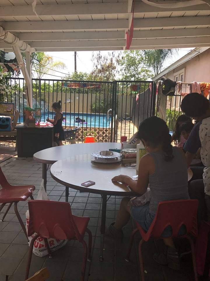 People sitting at a table on a patio with a child near a swimming pool