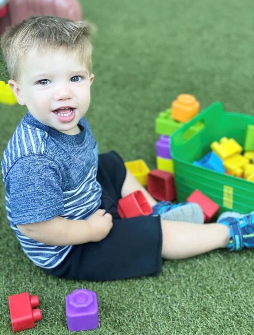 Child sitting on grass with colorful building blocks