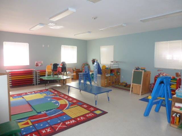 Empty classroom with colorful rug, small tables, and chairs