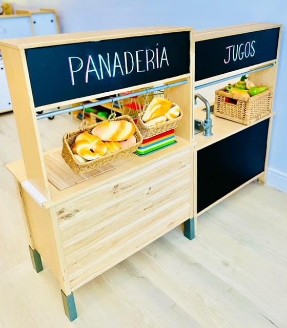 Wooden play stand with "PANADERIA" and "JUGOS" signs, baskets of play food