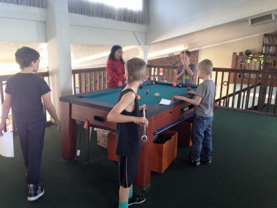 Children playing pool with adults nearby