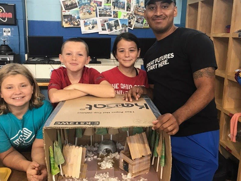 Adult and three children with a diorama made from a cardboard box