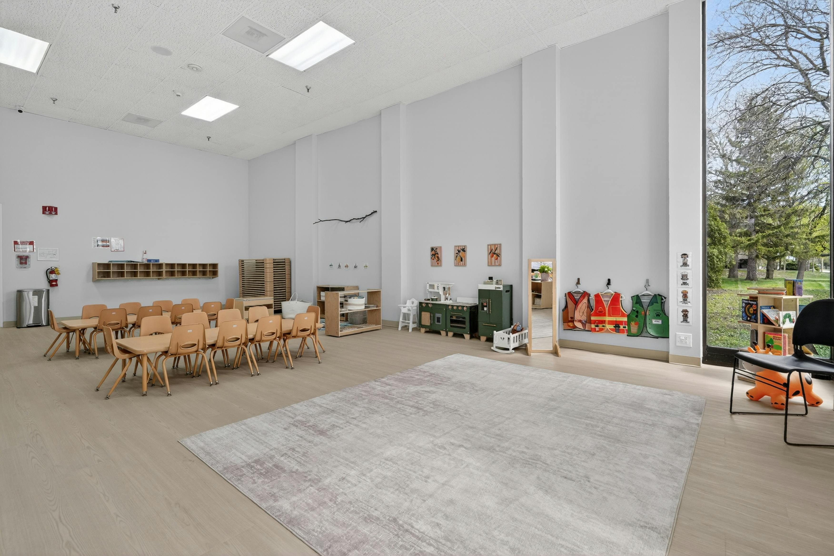 Classroom with small wooden tables and chairs and toy play area