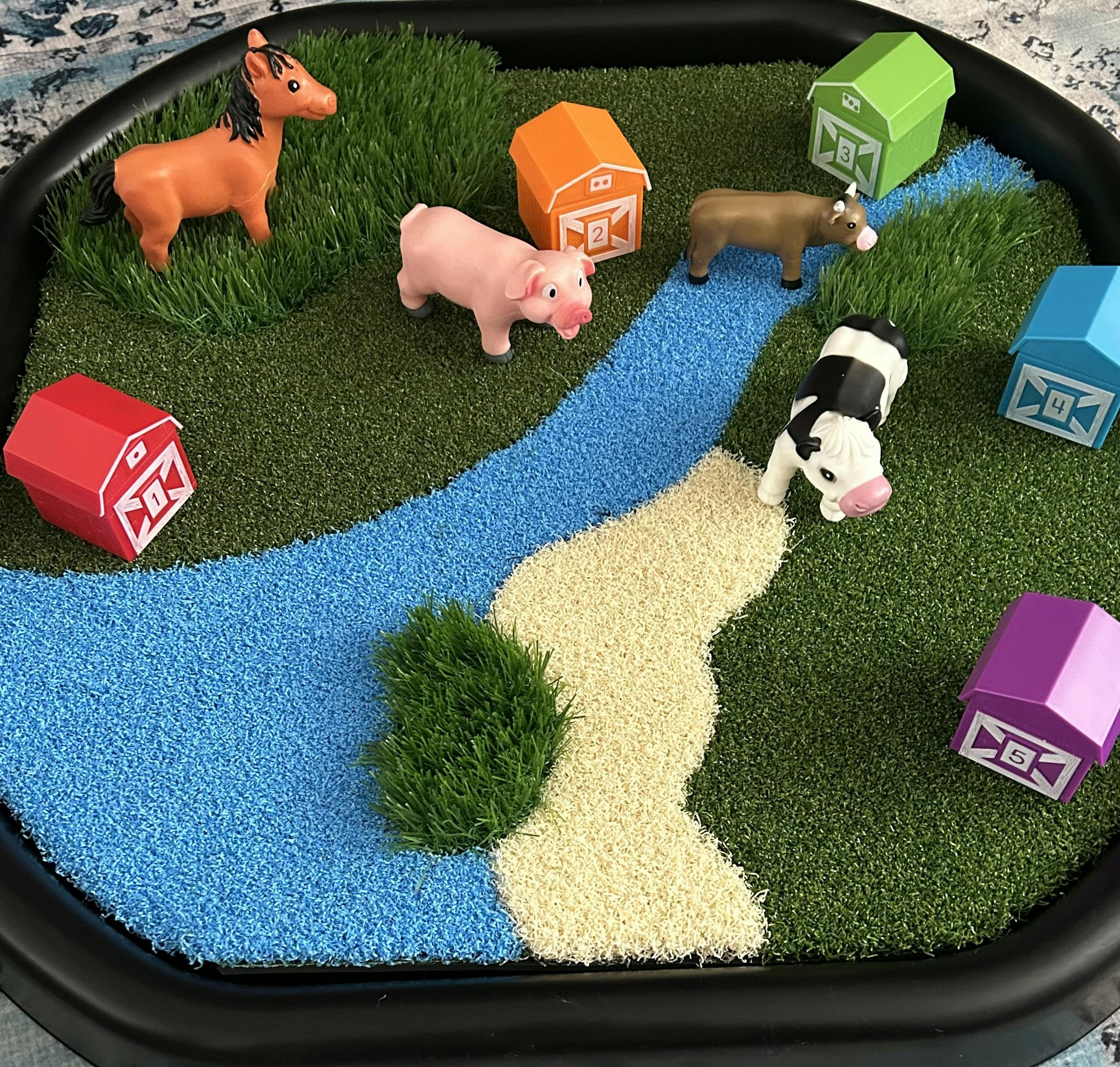 Toy farm animals and numbered barns on a miniature landscape mat