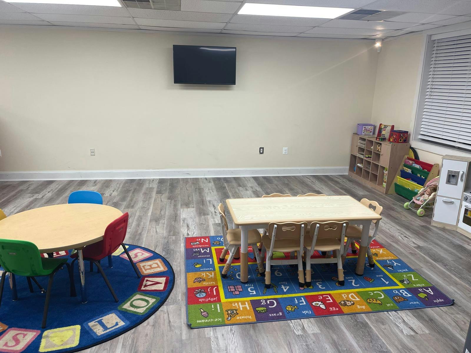 Classroom with small tables and chairs on alphabet rugs