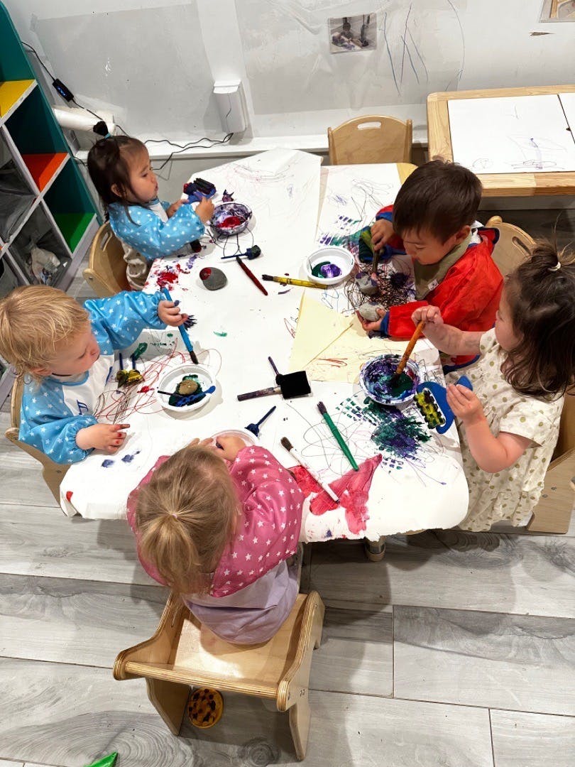 Four children painting at a table