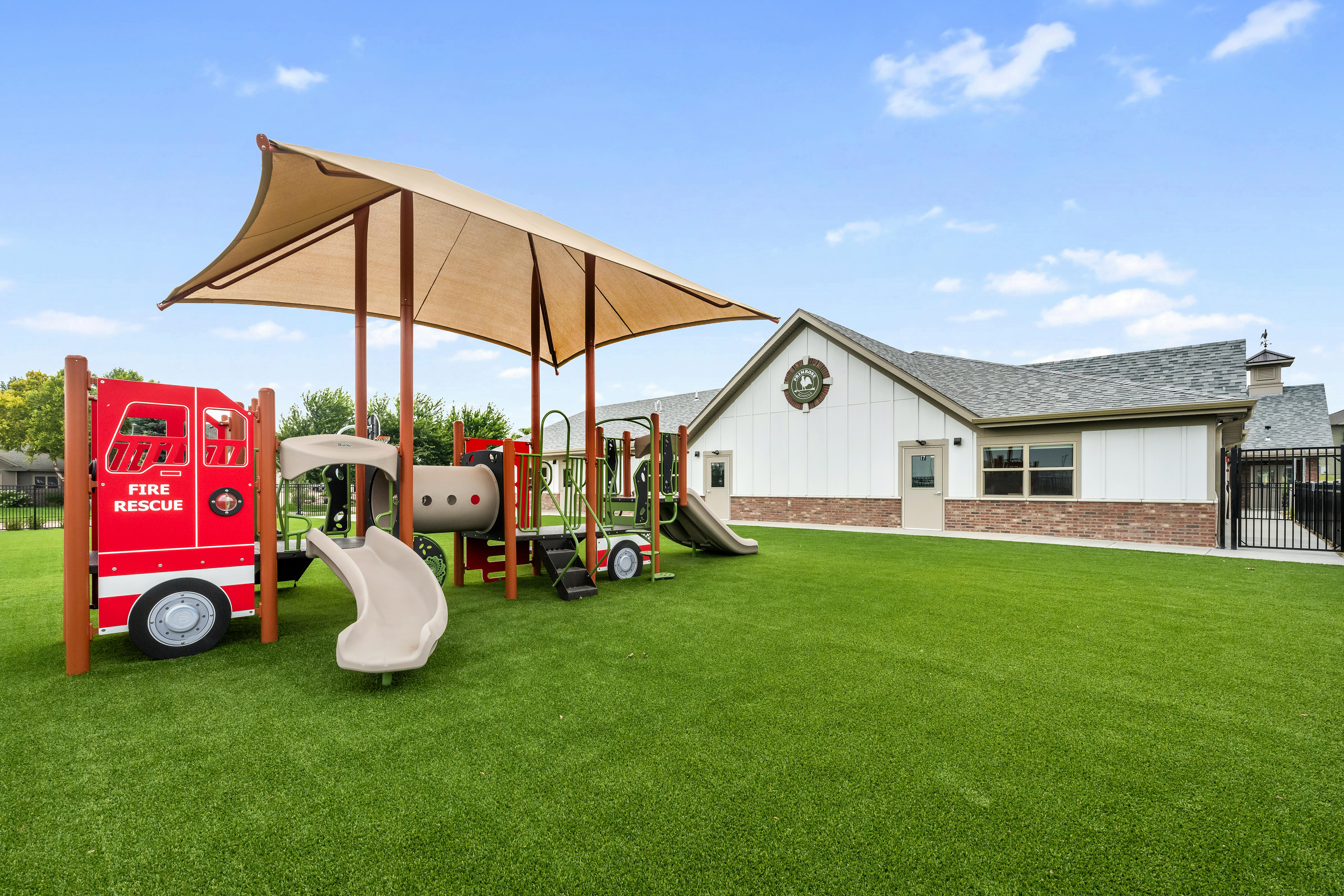 Playground with a fire truck play structure and slides on green turf