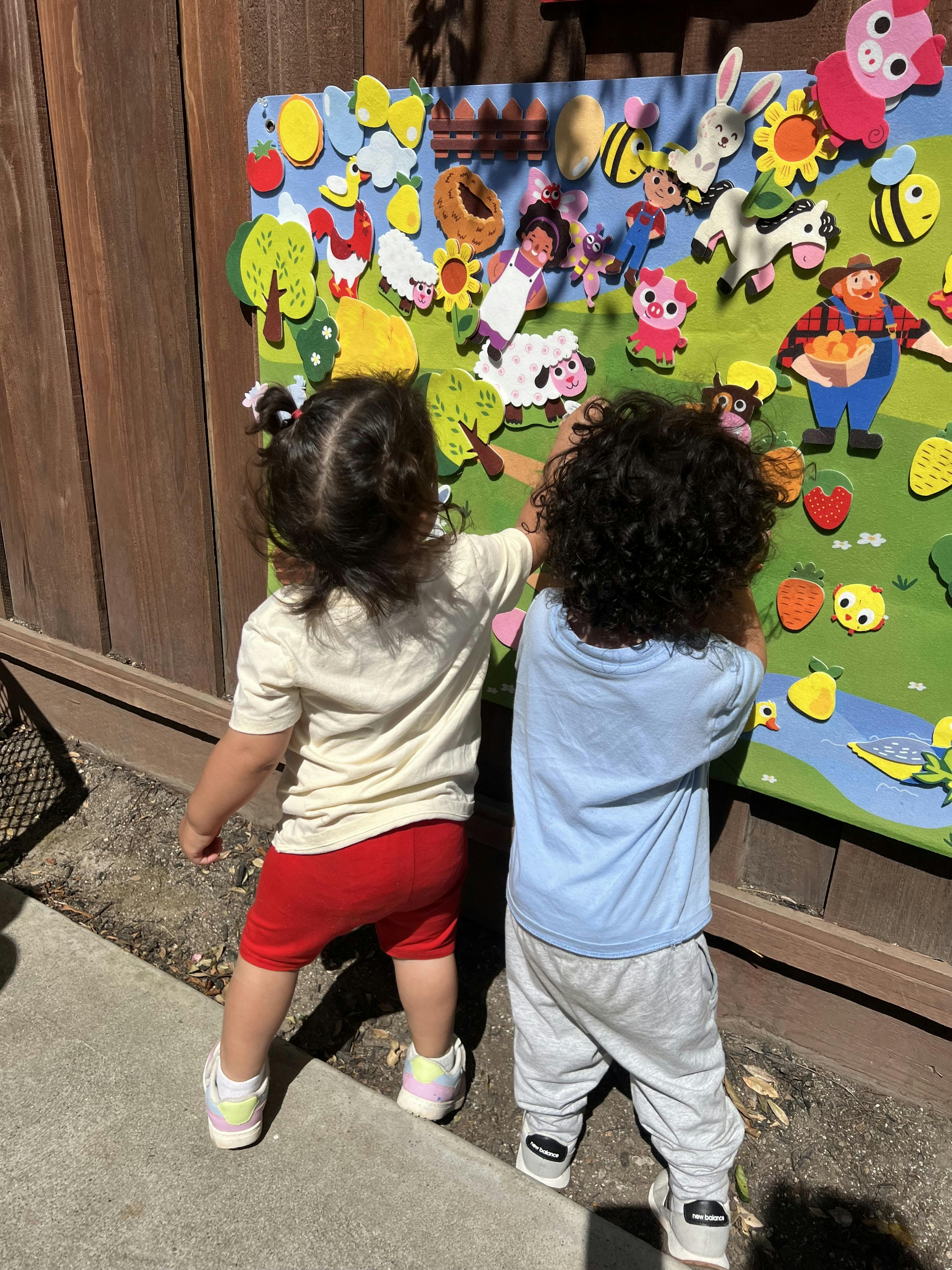 Two children playing with a felt board