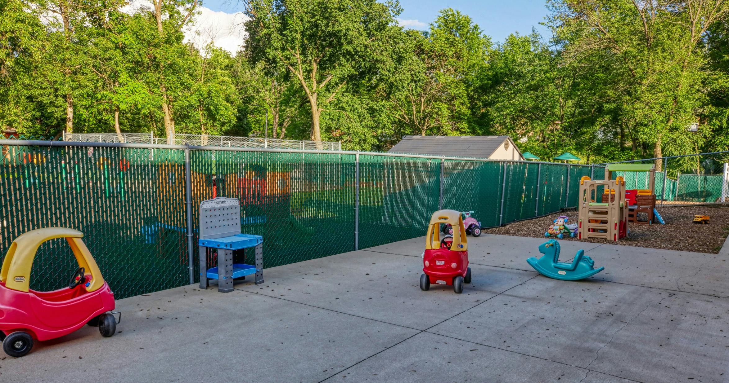 Outdoor play area with toy cars, a workbench, and a play structure
