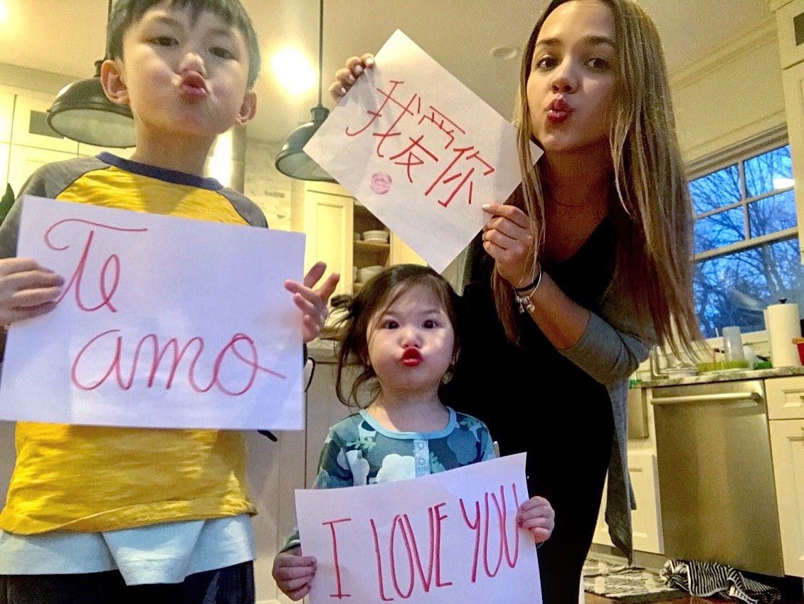 Three people holding signs that say "Te amo," "I love you," and Chinese characters