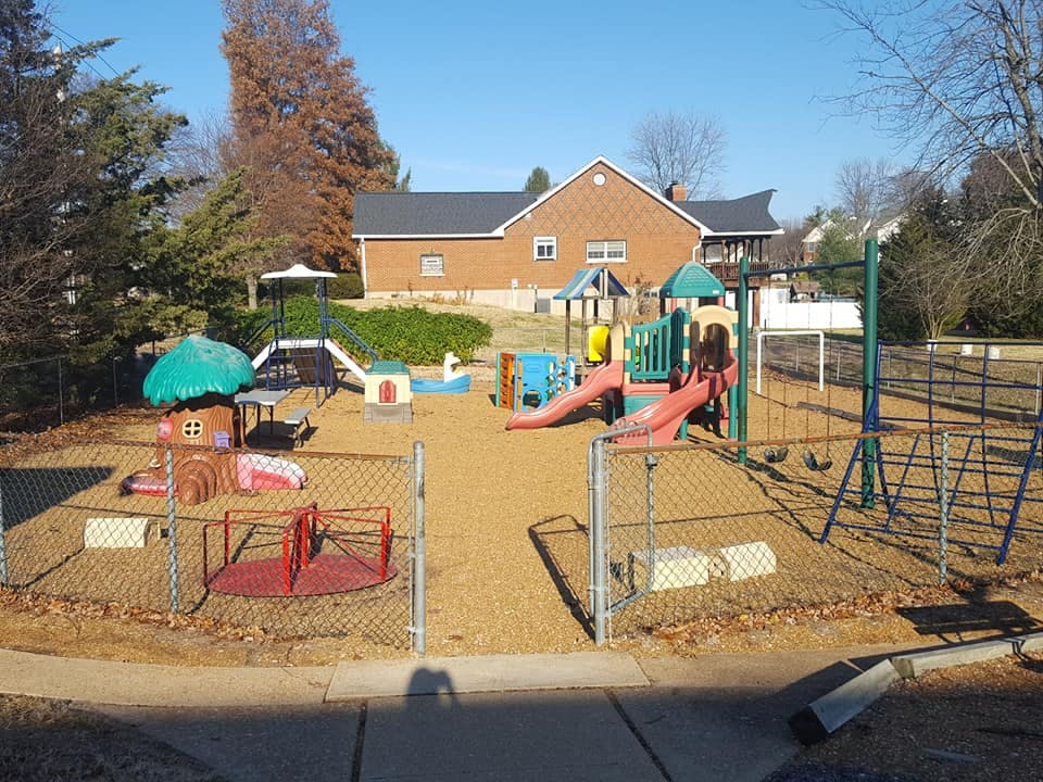 Outdoor playground with various colorful equipment and a building in the background