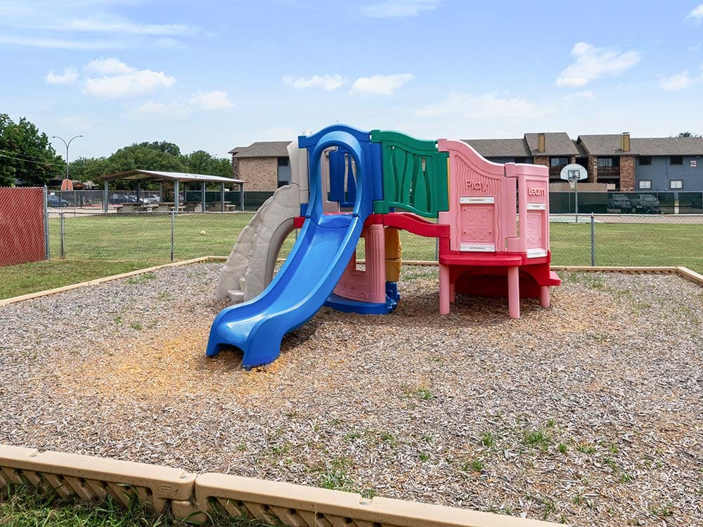 A colorful playground set with slides and climbing areas on wood chips