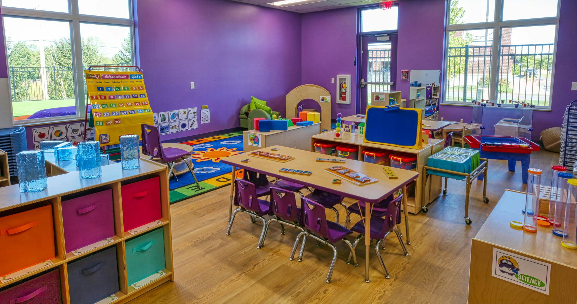 Classroom with purple walls, tables, chairs, and learning materials