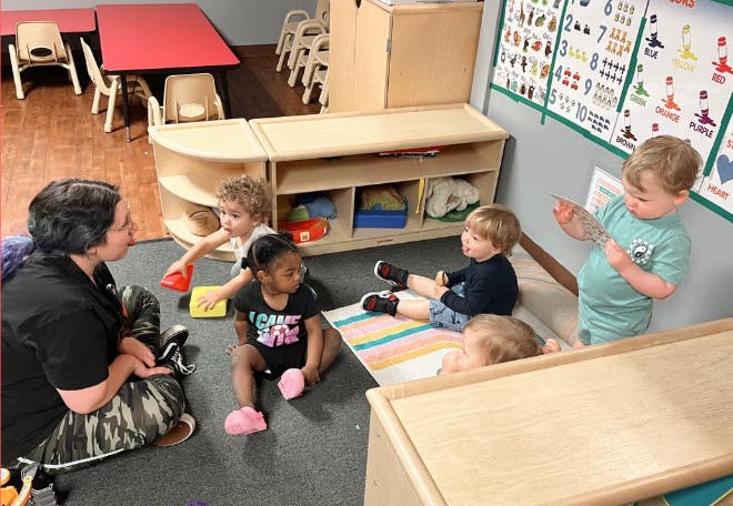 Adult and children playing on the floor in a classroom