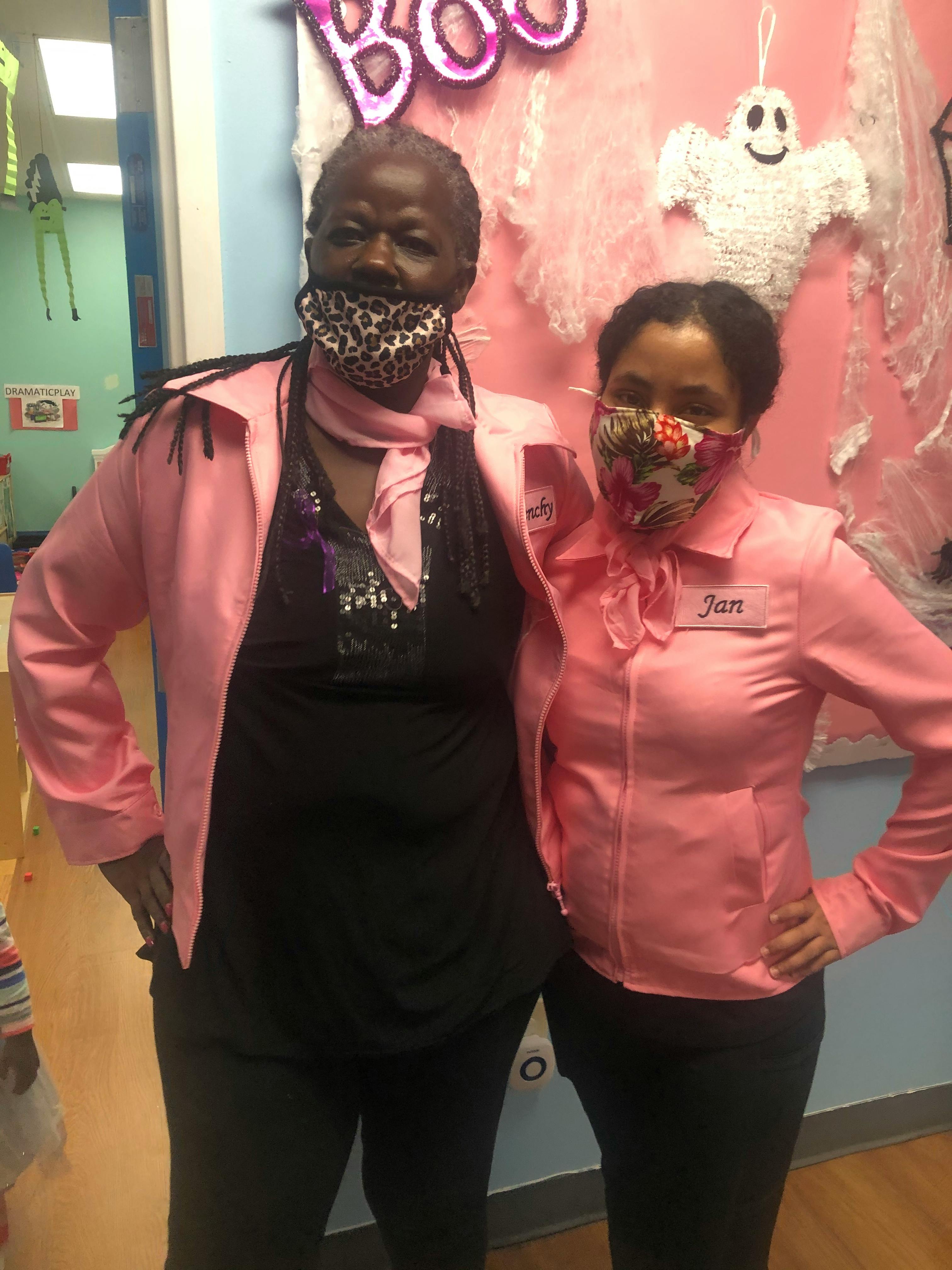 Two people wearing pink jackets and face masks