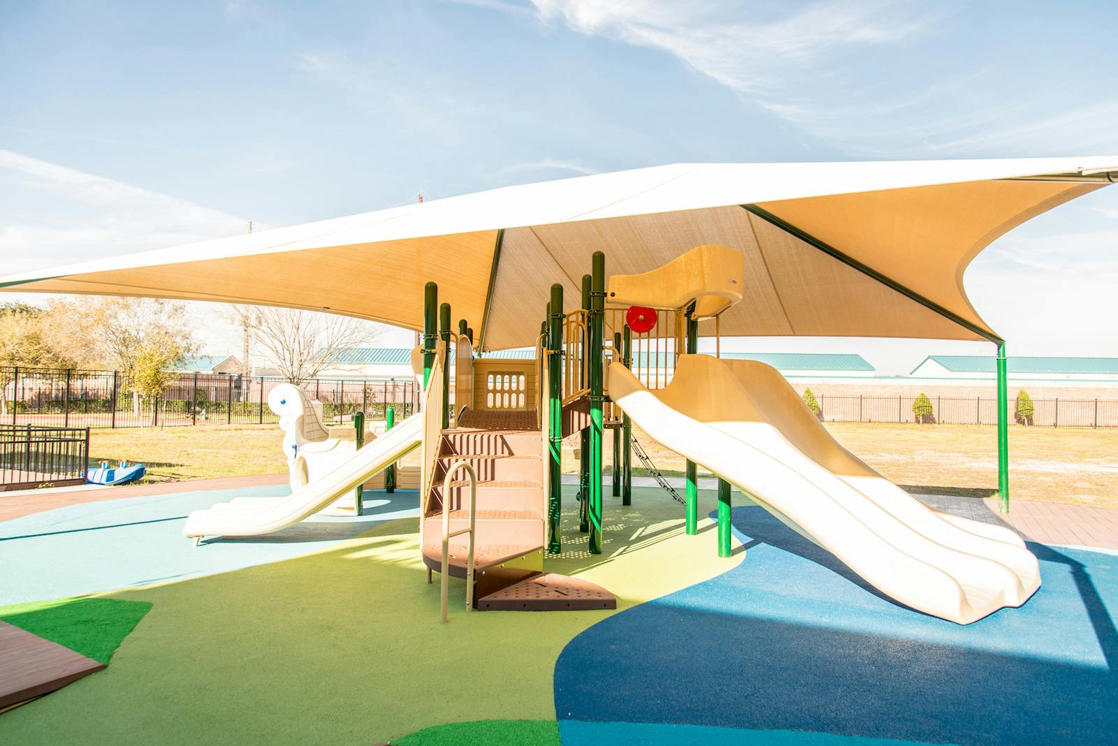 Playground with slides and climbing structures under a large shade canopy