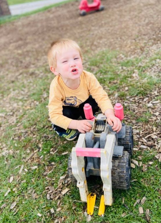 Child playing with a toy tractor outdoors