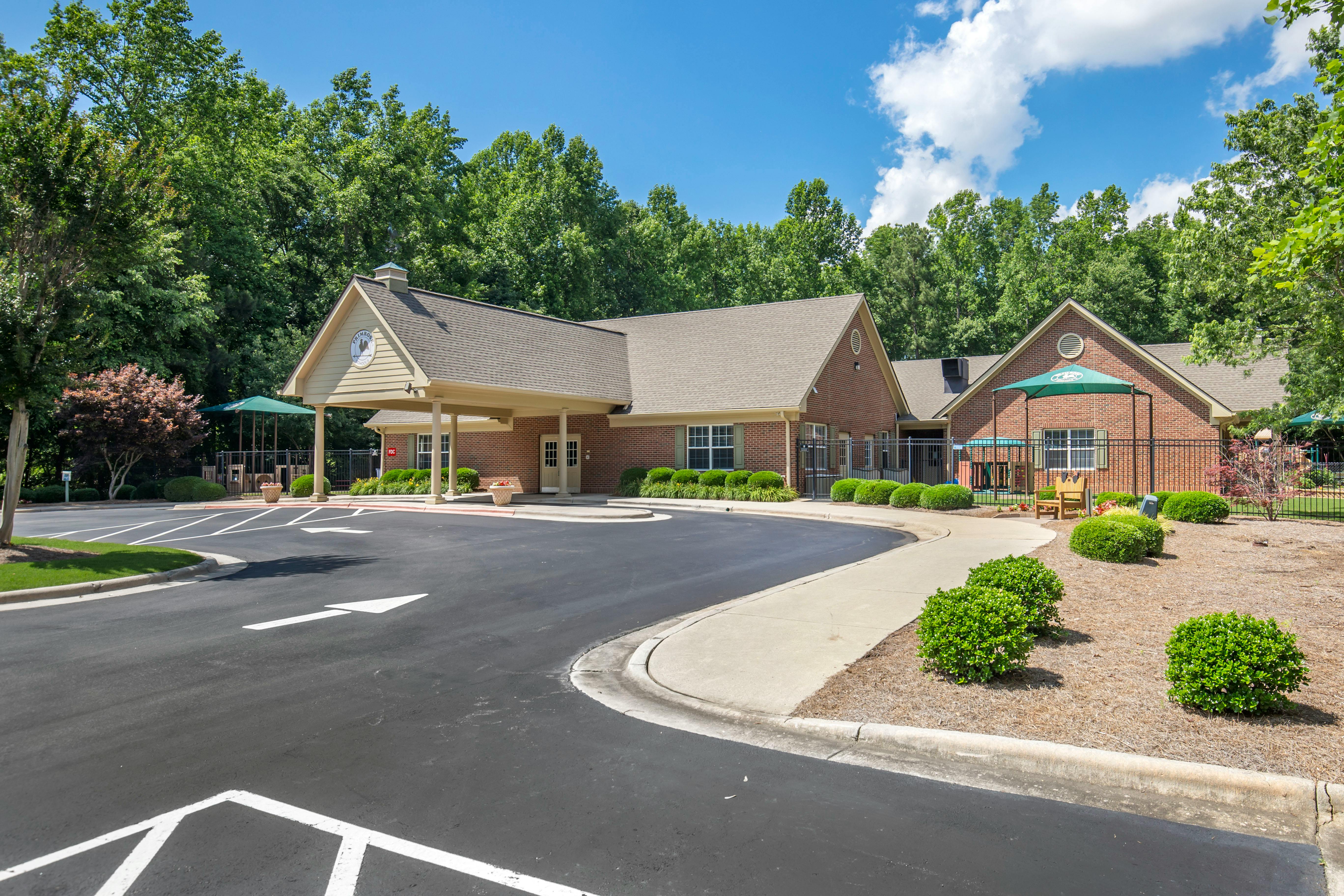 A brick building with a covered entrance and a parking lot in front