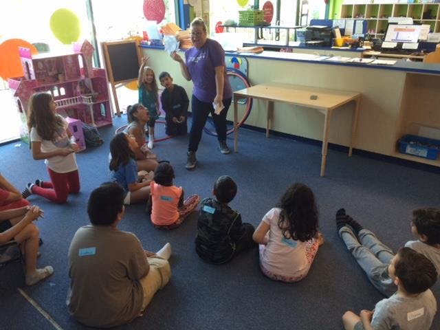 Adult speaking to children sitting on the floor in a classroom