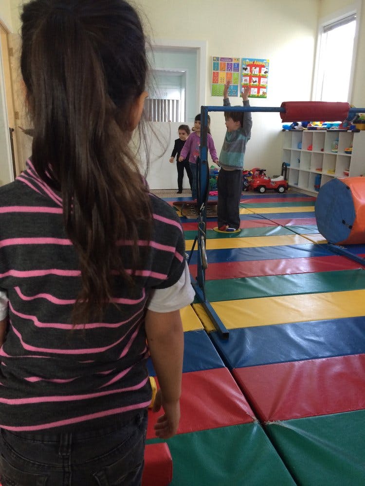 Child in foreground watching other children playing in a room