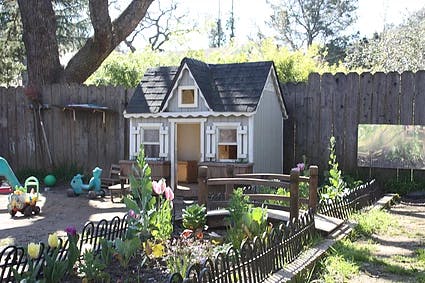 Playhouse in a backyard with a small garden and fence