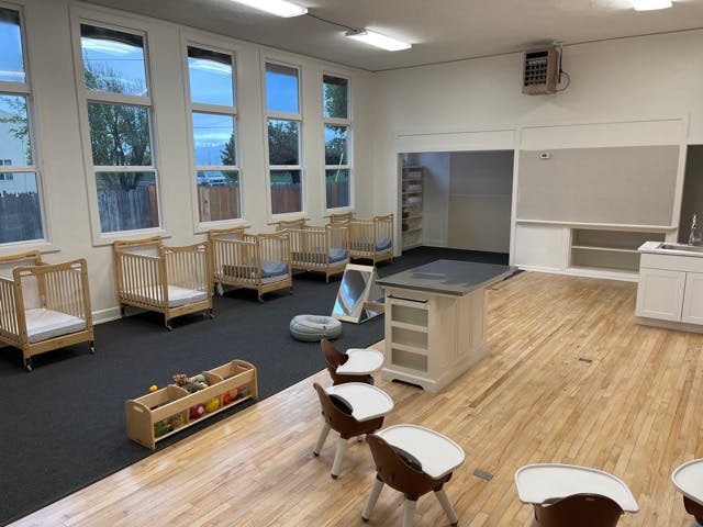 Empty room with cribs, small chairs, and a counter