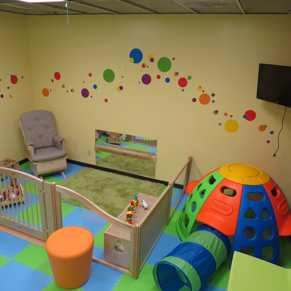 Playroom with colorful wall decals, playpen, and climbing toy