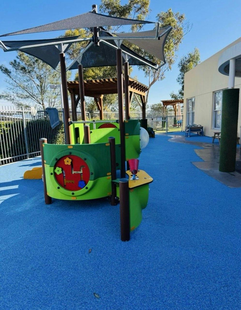 Playground equipment with a shade canopy on a blue rubber surface