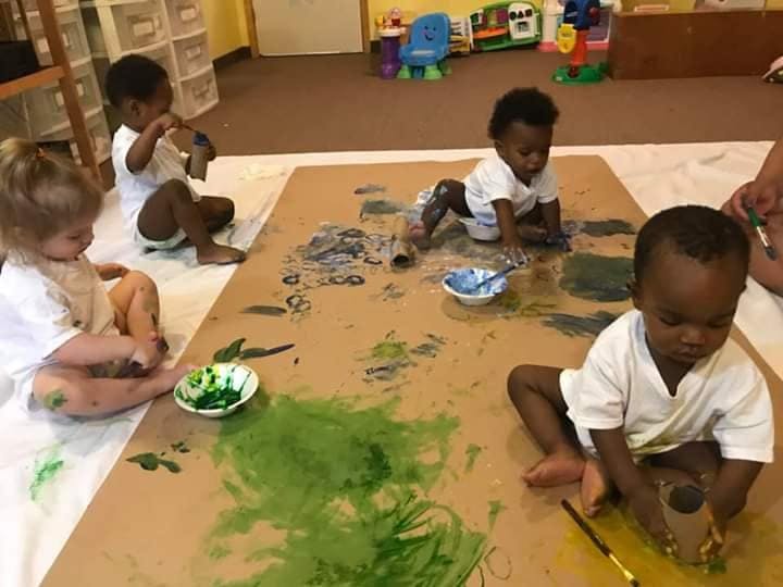 Children painting on a large sheet of paper on the floor